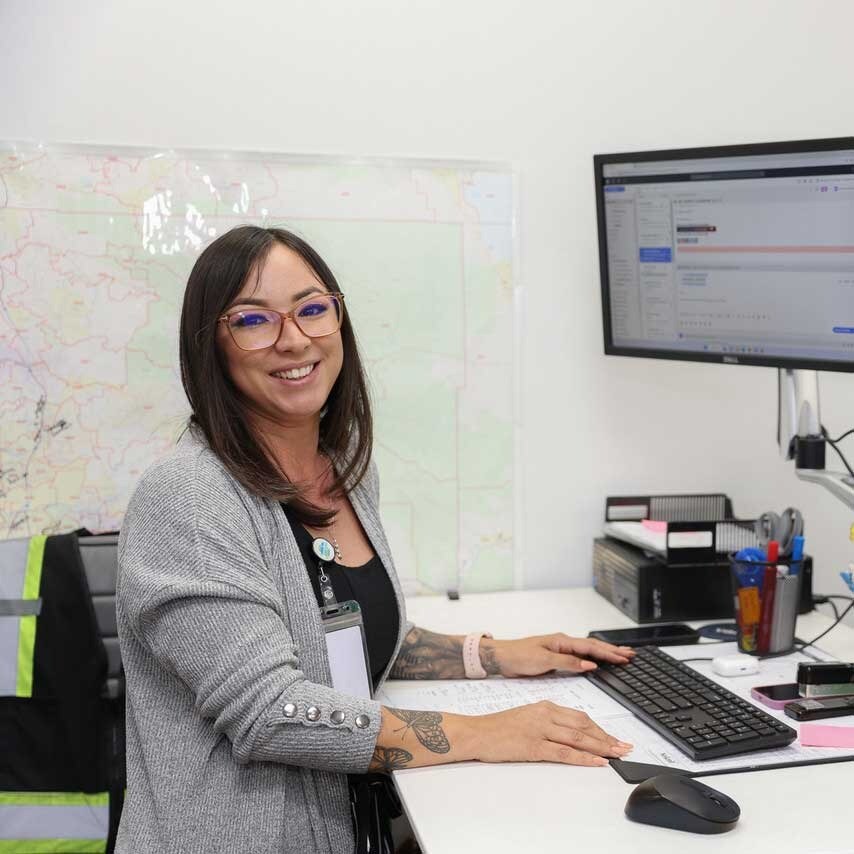 Female Employee At Desk Looking At Cam